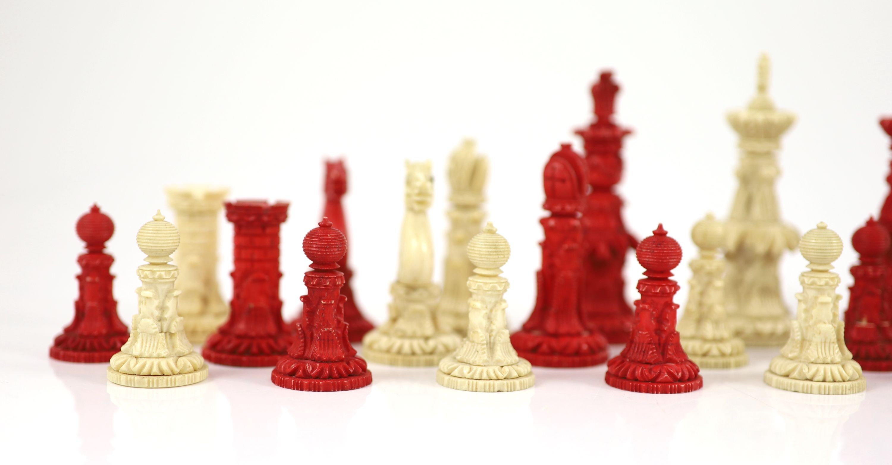 A 19th century Anglo-Indian white and stained bone chess set, with unusual carved palmate decoration, Kings 9.5cm.